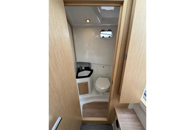Slide: The Image of Interior of 2025 Sargo 28 boat bathroom with sink, toilet, and wooden accents. - 18