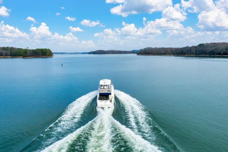Slide: The Image of 2006 Sea Ray 58 Sedan Bridge cruising on a serene lake under a blue sky. - 46