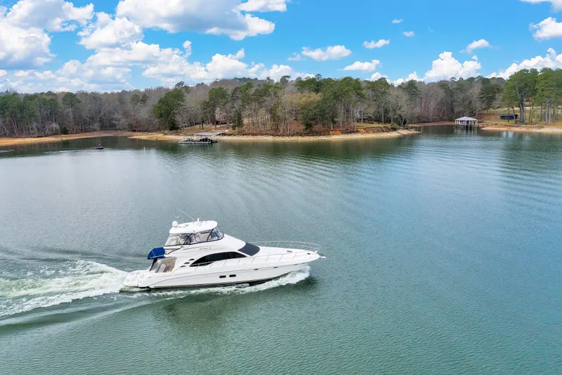 Slide: The Image of 2006 Sea Ray 58 Sedan Bridge cruising on a serene lake under a blue sky. - 47