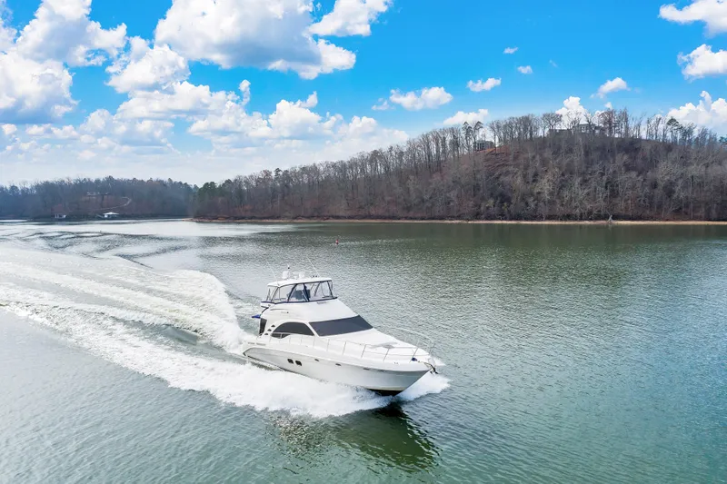 Slide: The Image of 2006 Sea Ray 58 Sedan Bridge cruising on a serene lake under a bright blue sky. - 6