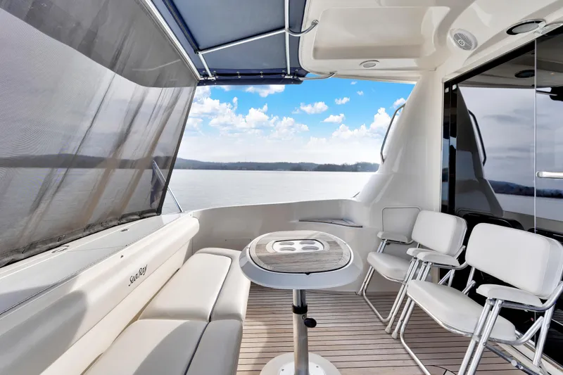 Slide: The Image of 2006 Sea Ray 58 Sedan Bridge yacht deck with seating and table, overlooking serene waters. - 8