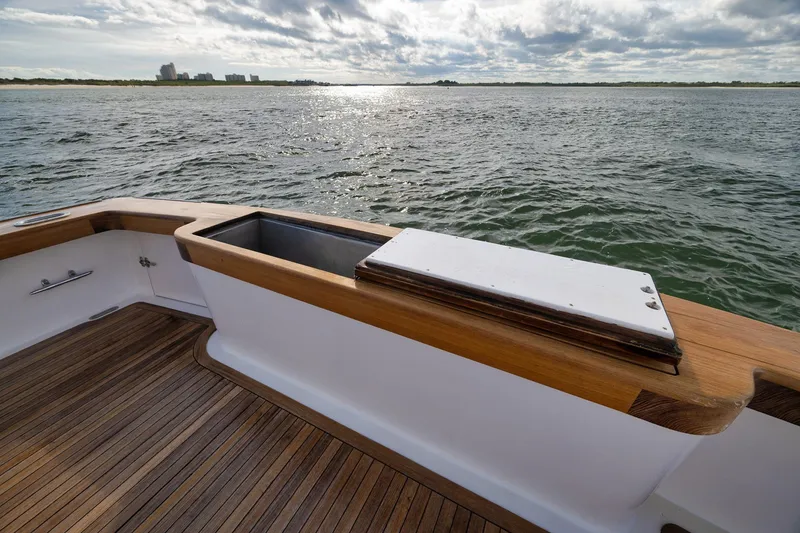 Slide: The Image of 2002 Paul Mann 60 Custom Carolina boat deck with wooden finish, overlooking calm waters. - 54