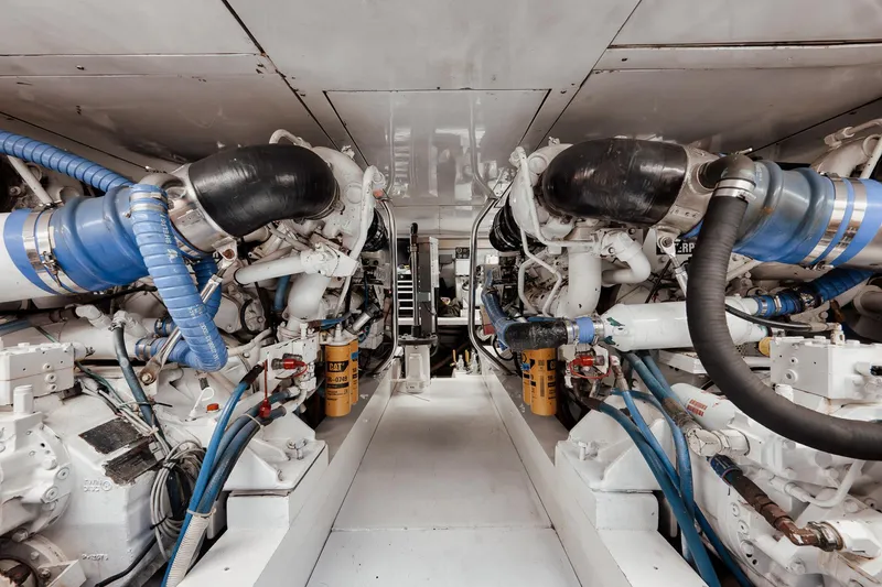 Slide: The Image of Engine room of 2002 Paul Mann 60 Custom Carolina yacht, featuring dual engines and blue hoses. - 57