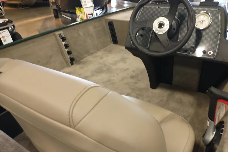 Slide: The Image of Interior of 2026 Tracker Bass Tracker Classic Limited boat with steering wheel and beige seating. - 2