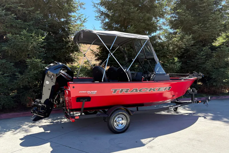 Slide: The Image of 2026 Tracker Pro Guide V-16 WT boat with canopy, parked outdoors. - 8