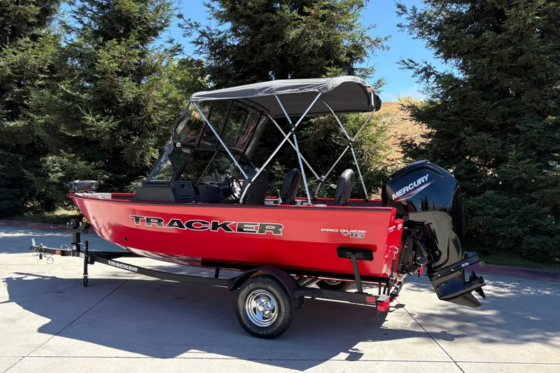 Slide: The Image of 2026 Tracker Pro Guide V-16 WT boat with Mercury engine, parked outdoors. - 6