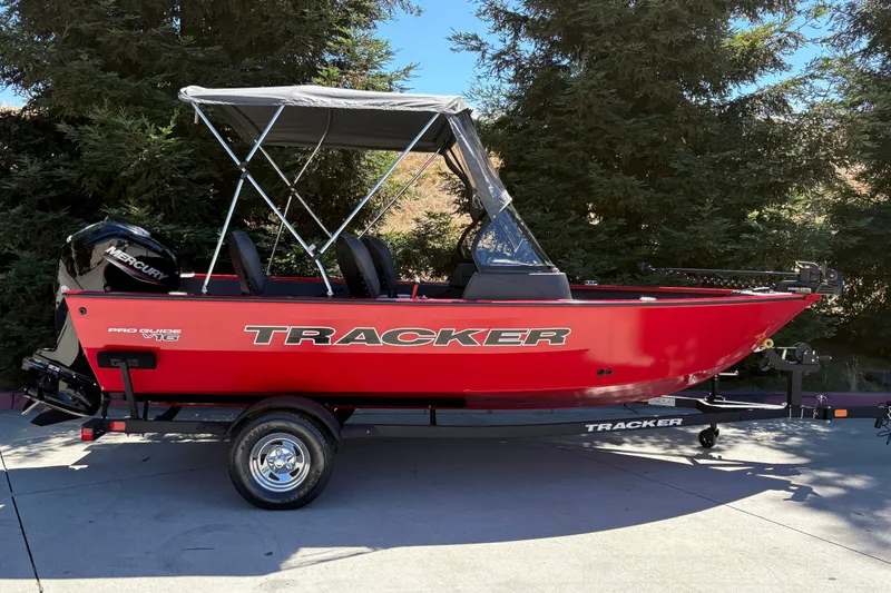 The Image of 2026 Tracker Pro Guide V-16 WT boat with canopy on trailer, parked outdoors. - 0