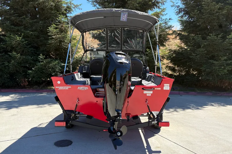 Slide: The Image of 2026 Tracker Pro Guide V-16 WT boat with canopy, parked outdoors. - 10
