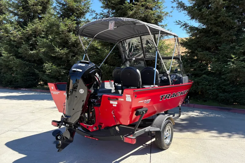 Slide: The Image of 2026 Tracker Pro Guide V-16 WT boat with canopy on trailer, parked outdoors. - 12