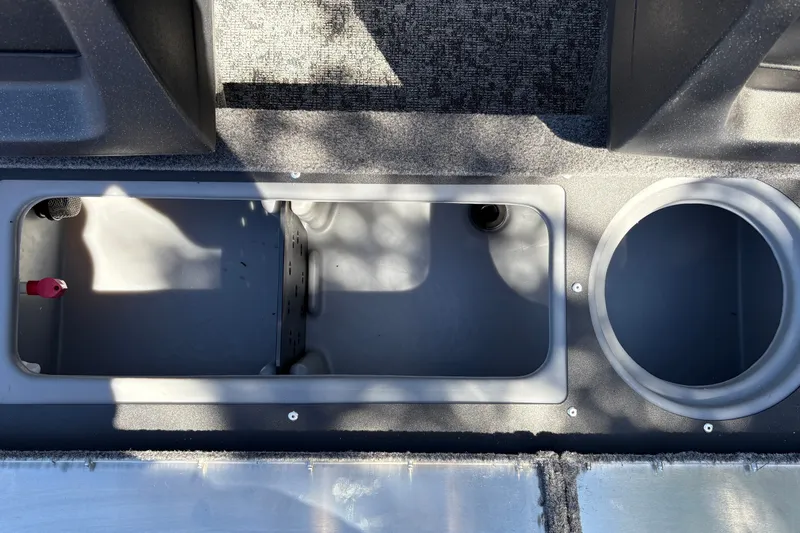 Slide: The Image of 2026 Tracker Pro Guide V-16 WT boat storage compartments, featuring carpeted flooring and circular holder. - 23
