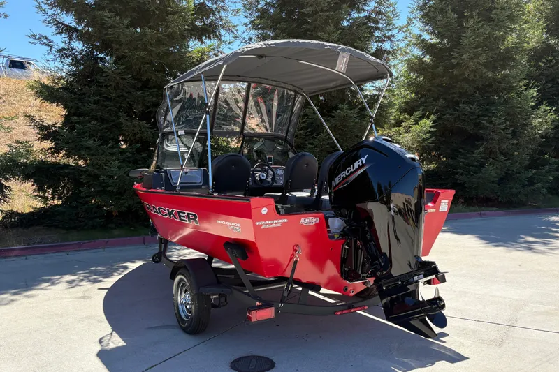 Slide: The Image of 2026 Tracker Pro Guide V-16 WT boat with Mercury engine, parked outdoors. - 9