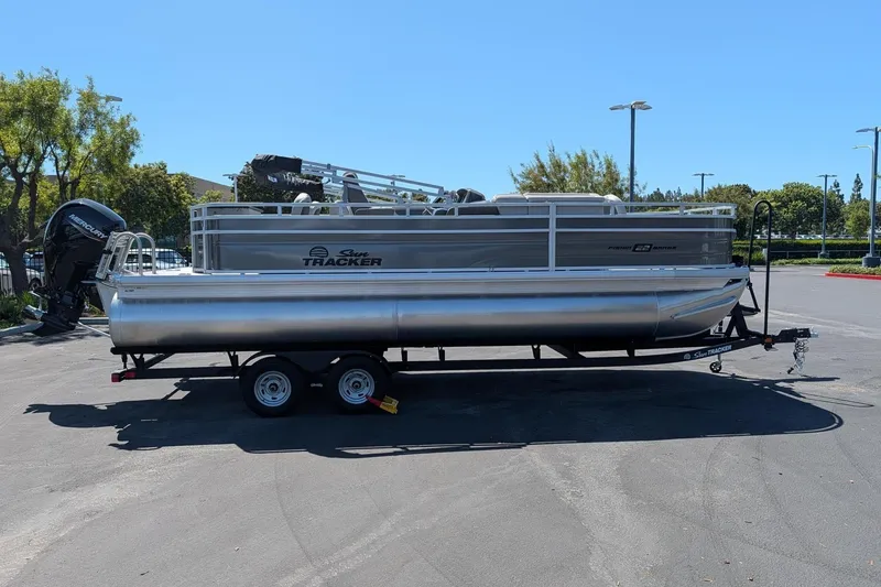 Slide: The Image of 2026 Sun Tracker Fishin' Barge 22 DLX pontoon boat on trailer in parking lot. - 3