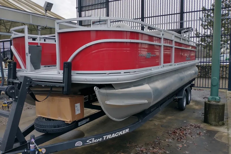 The Image of 2026 Sun Tracker Fishin' Barge 22 DLX pontoon boat on trailer, red exterior. - 0