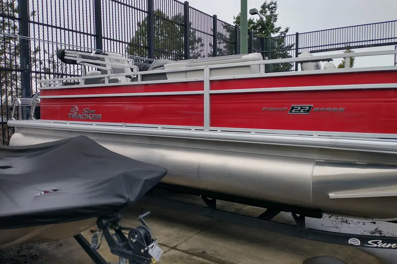 Slide: The Image of 2026 Sun Tracker Fishin' Barge 22 DLX pontoon boat, red exterior, parked outdoors. - 5