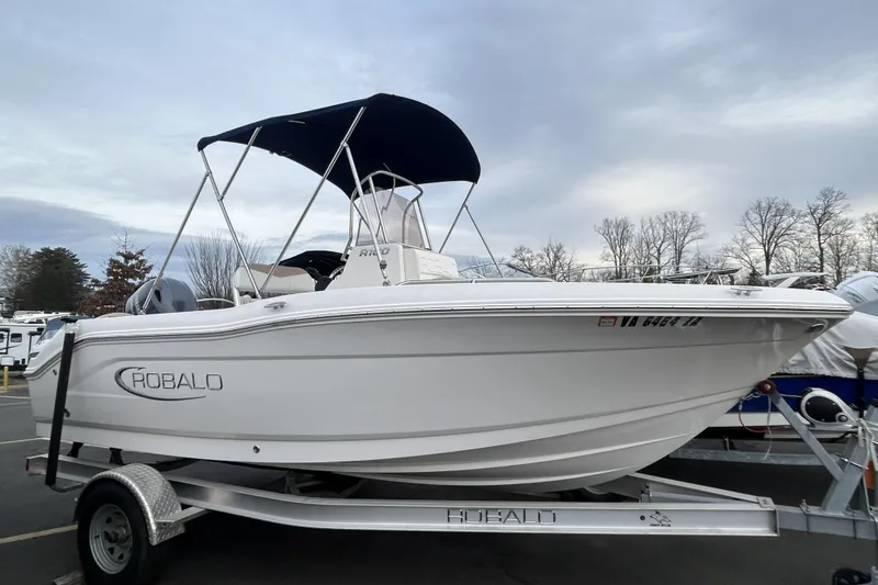 The Image of 2020 Robalo R180 Center Console boat on trailer, parked outdoors under cloudy sky. - 0