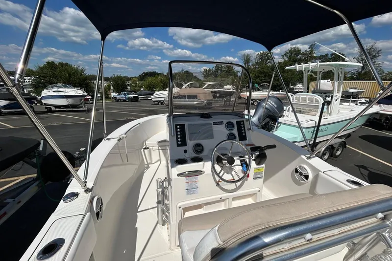 Slide: The Image of 2020 Robalo R180 Center Console boat with steering wheel, dashboard, and canopy in a marina. - 3