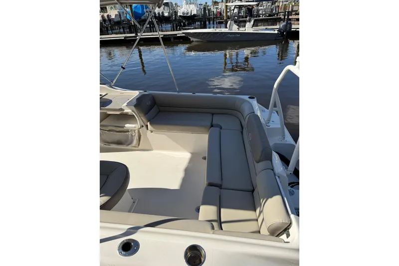Slide: The Image of 2022 Key West 239 DFS boat interior with cushioned seating at a marina. - 2