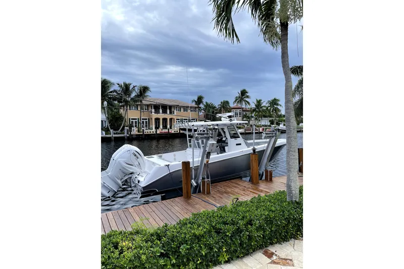 Slide: The Image of 2021 Everglades 335 Center Console boat on calm water, featuring sleek design and dual engines. - 1