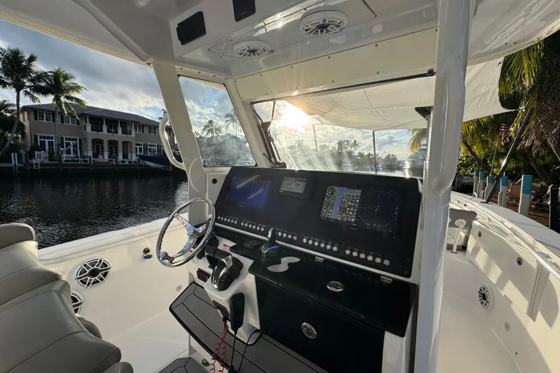 Slide: The Image of 2021 Everglades 335 Center Console boat interior with speakers and seating, under palm trees. - 15