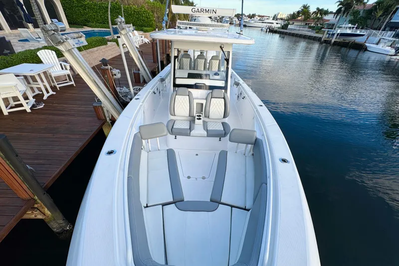 Slide: The Image of 2021 Everglades 335 Center Console boat interior with seating and table, docked near palm trees. - 29