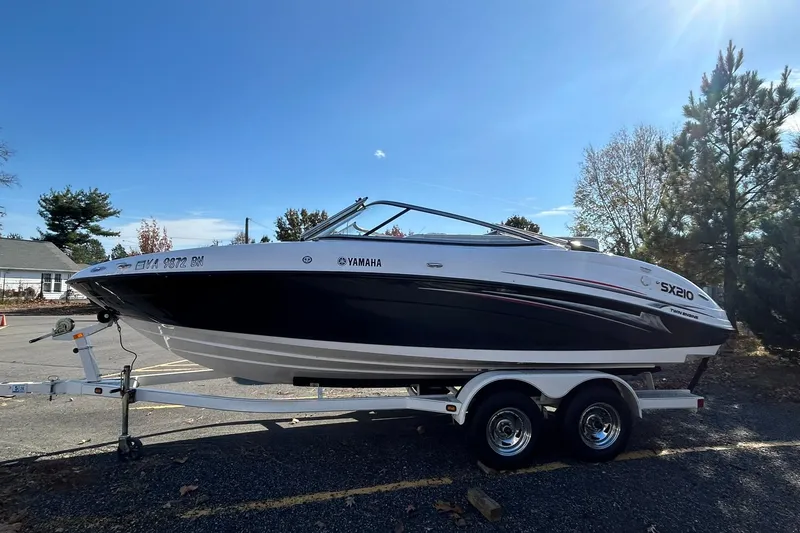 The Image of 2006 Yamaha Boats SX210 on trailer, parked outdoors under clear blue sky. - 0