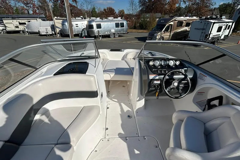 Slide: The Image of 2006 Yamaha Boats SX210 interior with steering wheel and seating, parked near RVs. - 6