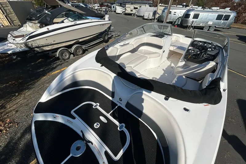 Slide: The Image of 2006 Yamaha Boats SX210 with sleek interior, parked near other boats and trailers. - 7