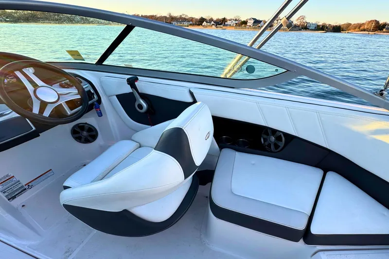 Slide: The Image of 2018 Regal 21 OBX boat interior with white seating and steering wheel, on calm water. - 12