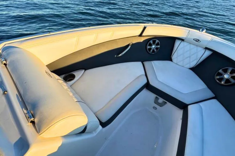 Slide: The Image of 2018 Regal 21 OBX boat interior with cushioned seating and cup holders on calm water. - 18