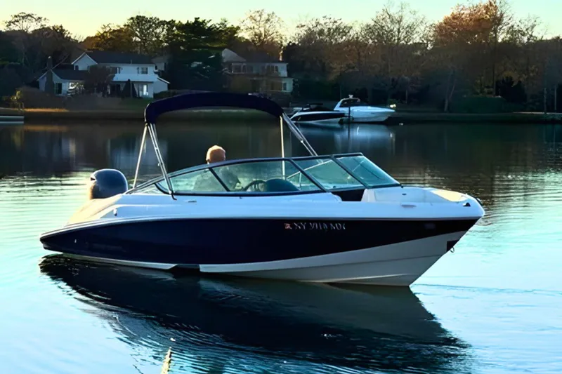 Slide: The Image of 2018 Regal 21 OBX boat cruising on a serene lake near waterfront homes. - 4