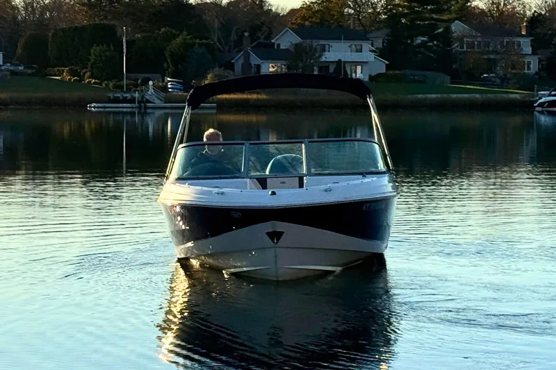 Slide: The Image of 2018 Regal 21 OBX boat cruising on a calm lake near residential area. - 6