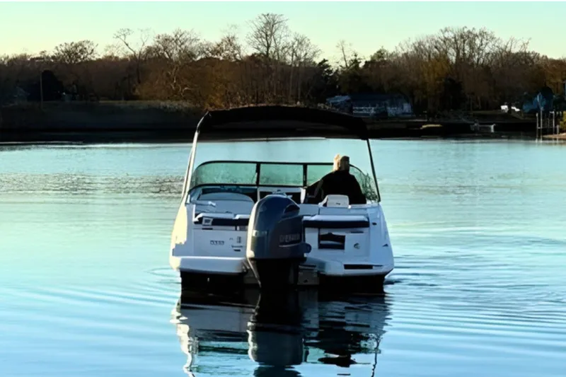 Slide: The Image of 2018 Regal 21 OBX boat cruising on a calm lake with trees in the background. - 7