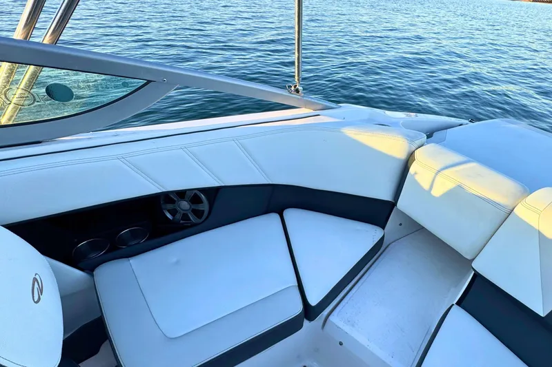 Slide: The Image of 2018 Regal 21 OBX boat interior with white seating and cup holders on calm water. - 9