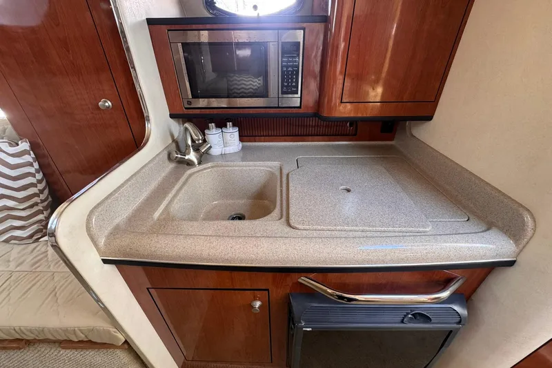 Slide: The Image of 2007 Sea Ray 280 Sundancer galley with sink, microwave, and storage cabinets. - 18