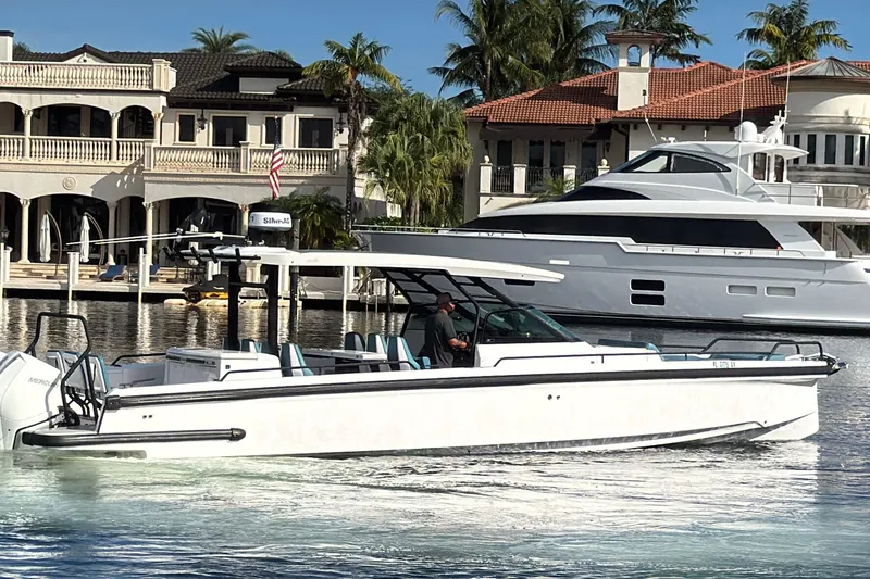 Slide: The Image of 2021 Axopar 37 Sun Top boat cruising near luxury waterfront homes. - 2