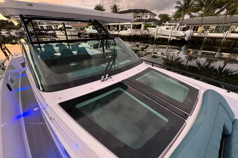 Slide: The Image of 2021 Axopar 37 boat docked, featuring sleek design and modern seating, with waterfront view. - 25