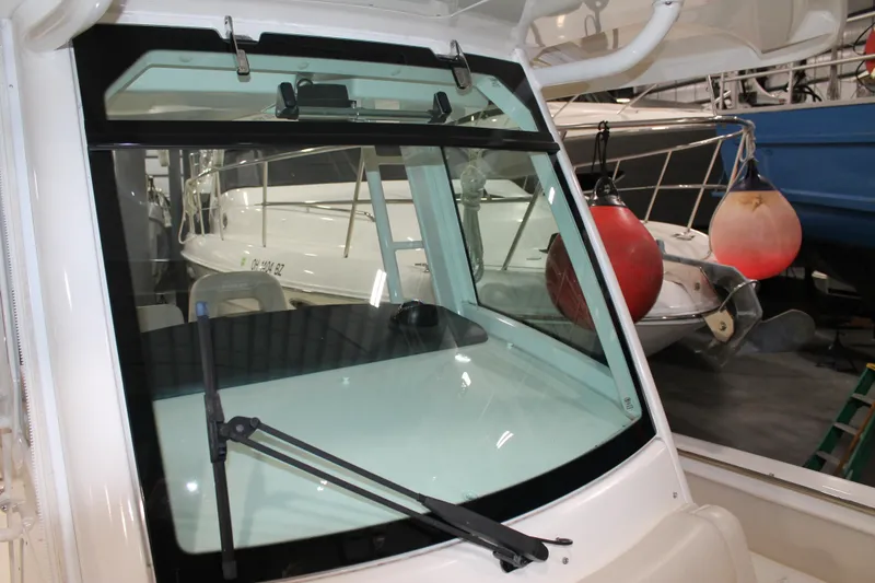 Slide: The Image of 2017 Boston Whaler 330 Outrage boat windshield with wiper in a marina setting. - 60