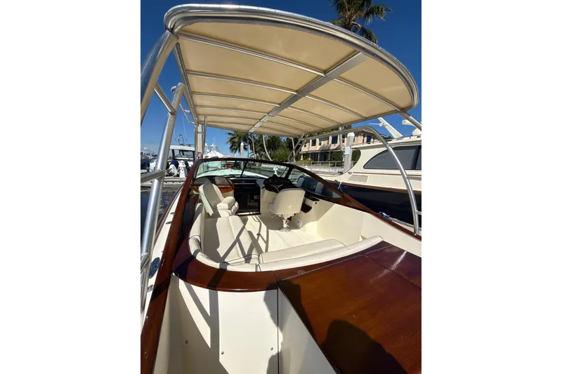 Slide: The Image of 2005 Hinckley Talaria 29 Runabout with canopy, docked under clear blue sky. - 3