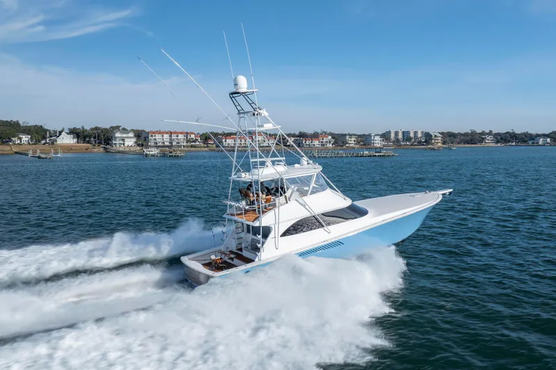 Slide: The Image of 2009 Viking 60 Convertible yacht cruising on open water near coastal buildings. - 18