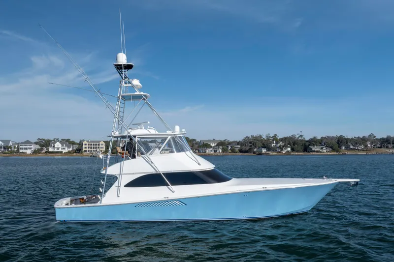 Slide: The Image of 2009 Viking 60 Convertible yacht on calm water, with coastal homes in the background. - 9