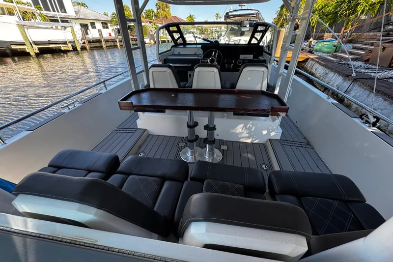 Slide: The Image of 2017 Axopar 37 Sun Top boat interior with seating and table, docked by waterfront homes. - 11
