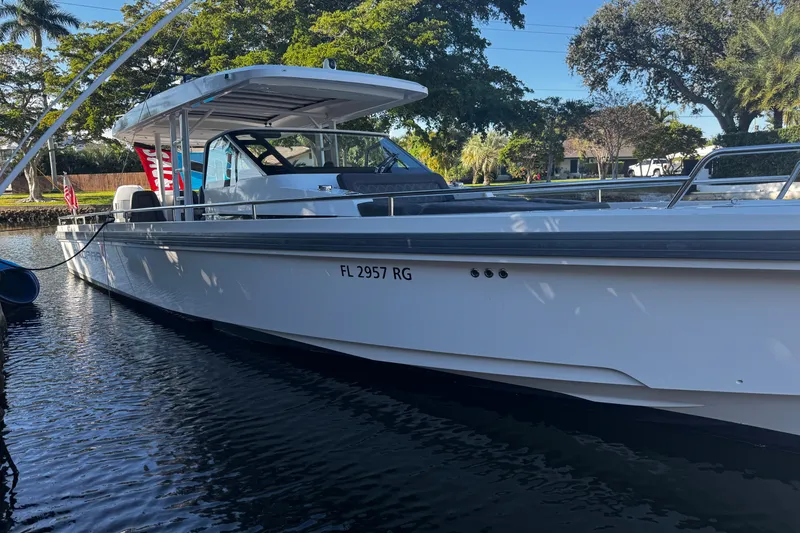 Slide: The Image of 2017 Axopar 37 Sun Top boat docked on a sunny day, surrounded by trees. - 2