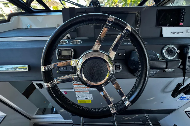 Slide: The Image of Steering wheel of 2017 Axopar 37 Sun Top boat, featuring modern dashboard controls. - 26