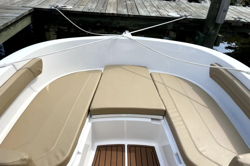 Slide: The Image of 2024 Trophy CC22 boat interior with beige seating and wooden deck, docked at a pier. - 4