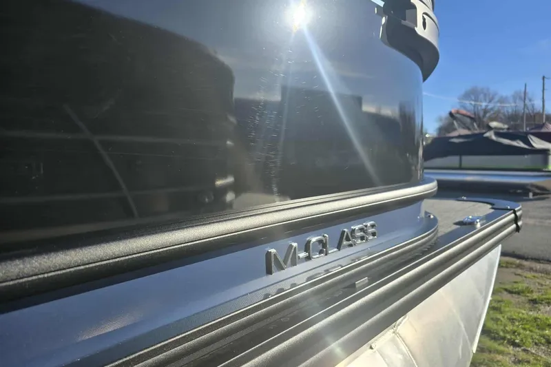 Slide: The Image of 2026 Qwest 8524 Q3XA M-Class boat, sleek design, reflective surface, outdoor setting. - 2