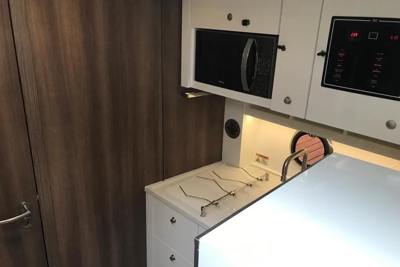 Slide: The Image of 2023 Evolve 400HT interior kitchen with microwave, modern cabinetry, and sleek design. - 12