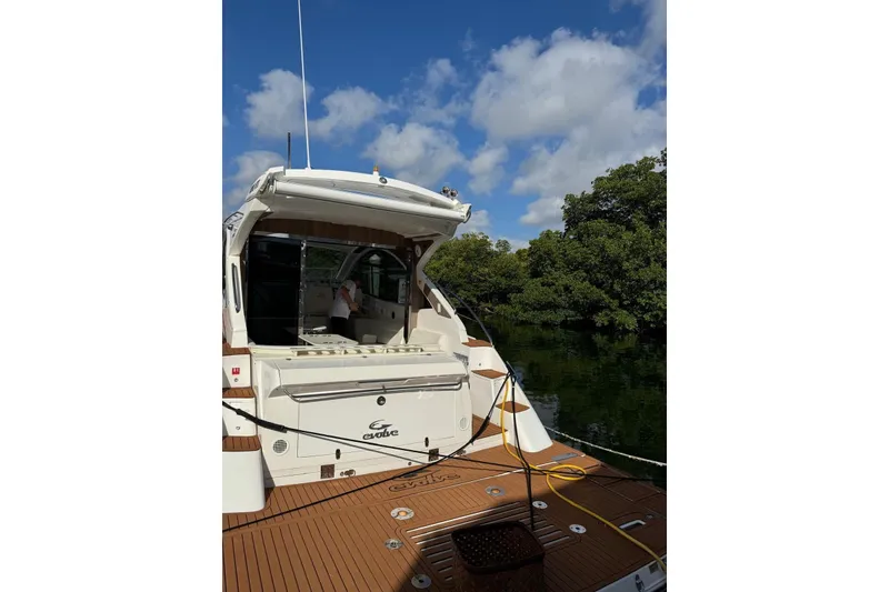 Slide: The Image of 2023 Evolve 400HT yacht docked, featuring open deck and lush greenery backdrop. - 14