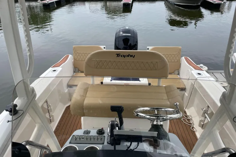 Slide: The Image of 2024 Trophy CC22 boat interior with beige seating and steering wheel at a marina. - 5