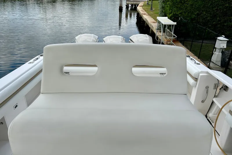 Slide: The Image of 2012 Intrepid 400 Cuddy boat interior with white cushioned seating by the water. - 14