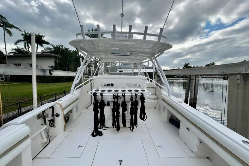 Slide: The Image of 2012 Intrepid 400 Cuddy boat deck with fishing rod holders, docked by a waterfront. - 9